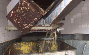 Rusty metal bin chute being cleaned in an industrial wash station at London Bin Cleaning, showcasing professional waste container sanitation services in London.
