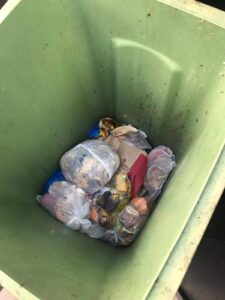 Discarded garbage bags inside a green bin, ready for collection, demonstrating professional bin cleaning services.